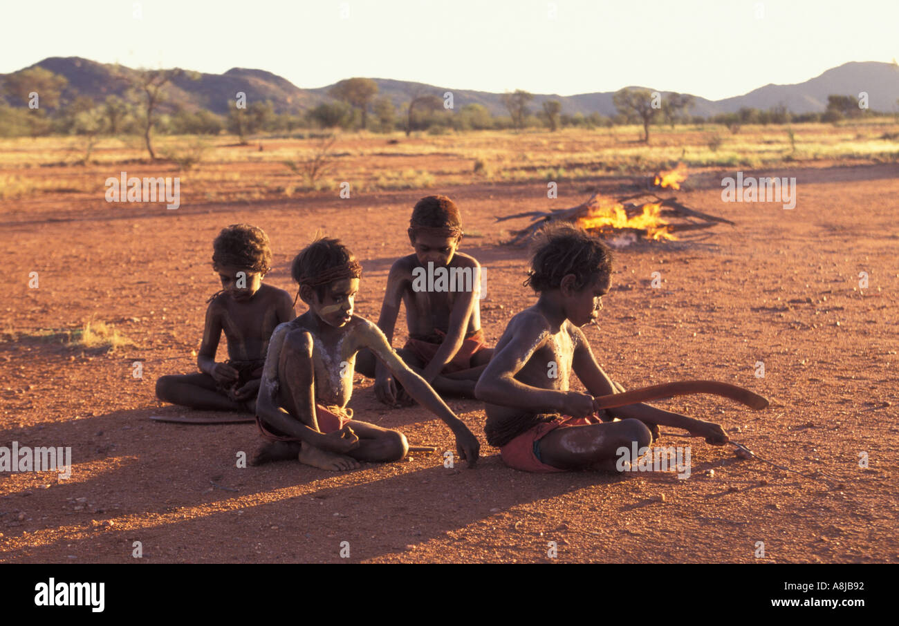 Aboriginal boys painted up for ceremony play with boomerangs in remote desert Central Australia Stock Photo