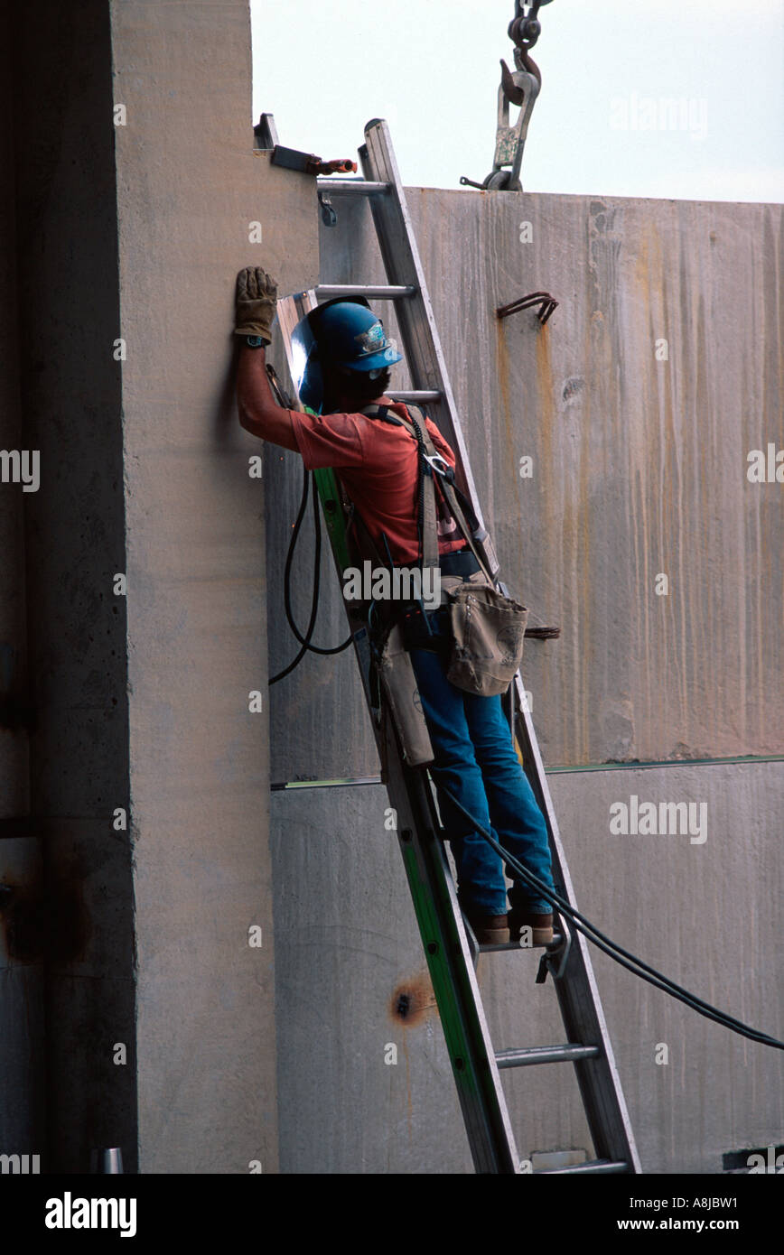 Masked man on ladder welding at construction site Stock Photo