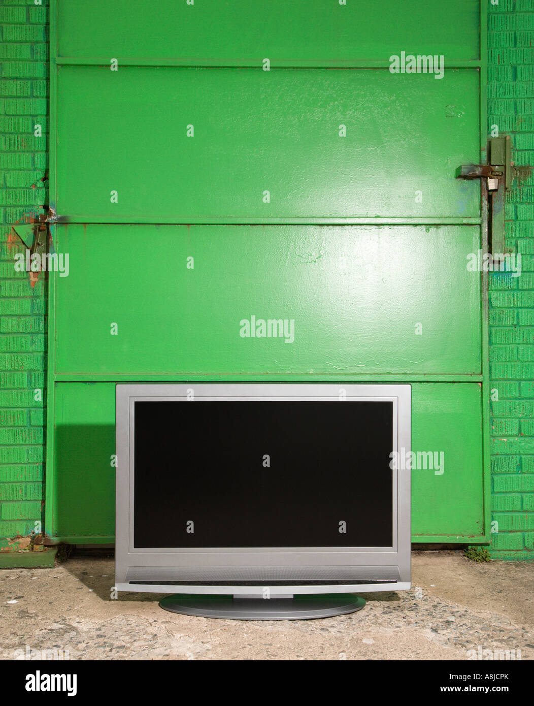 Flat panel television in front of green metal door Stock Photo