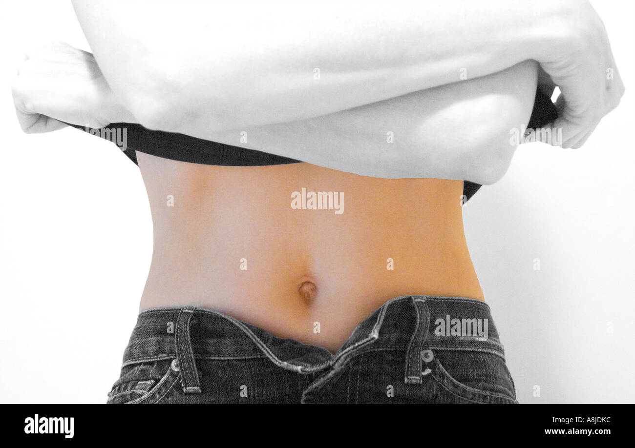 female removing tee shirt bare midriff jeans partially unbuttoned Stock Photo