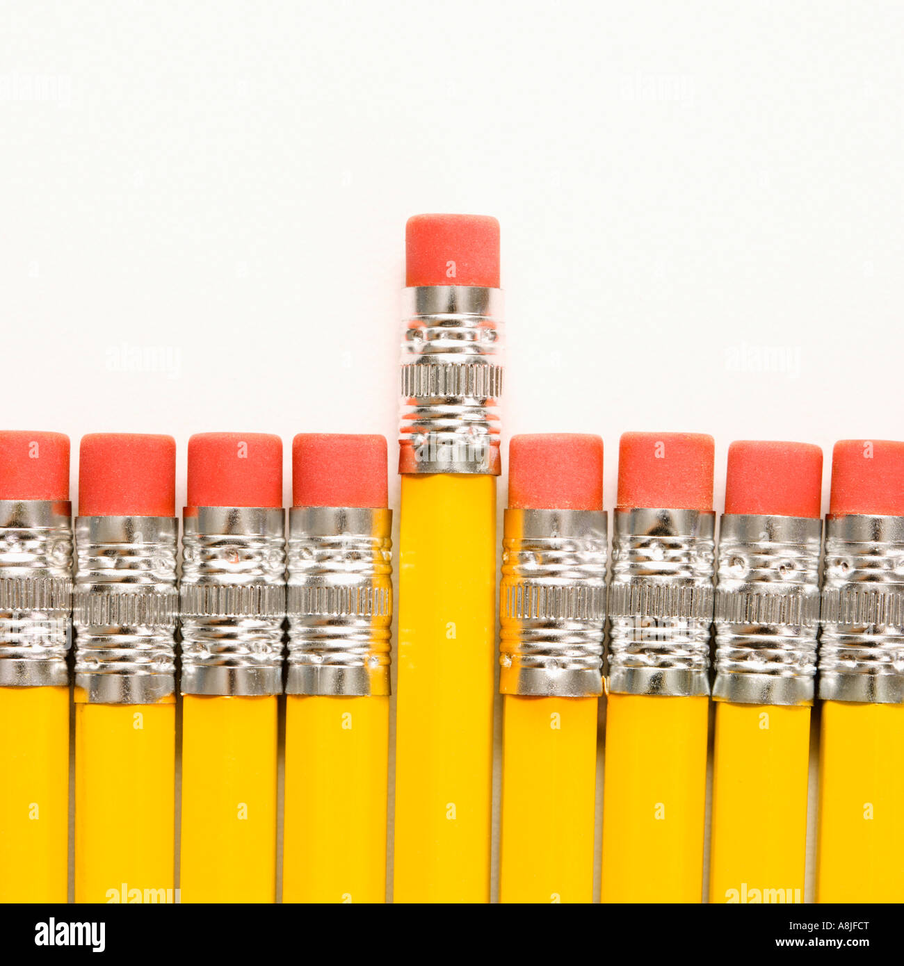 Even row of eraser ends of pencils with one raised higher than the rest