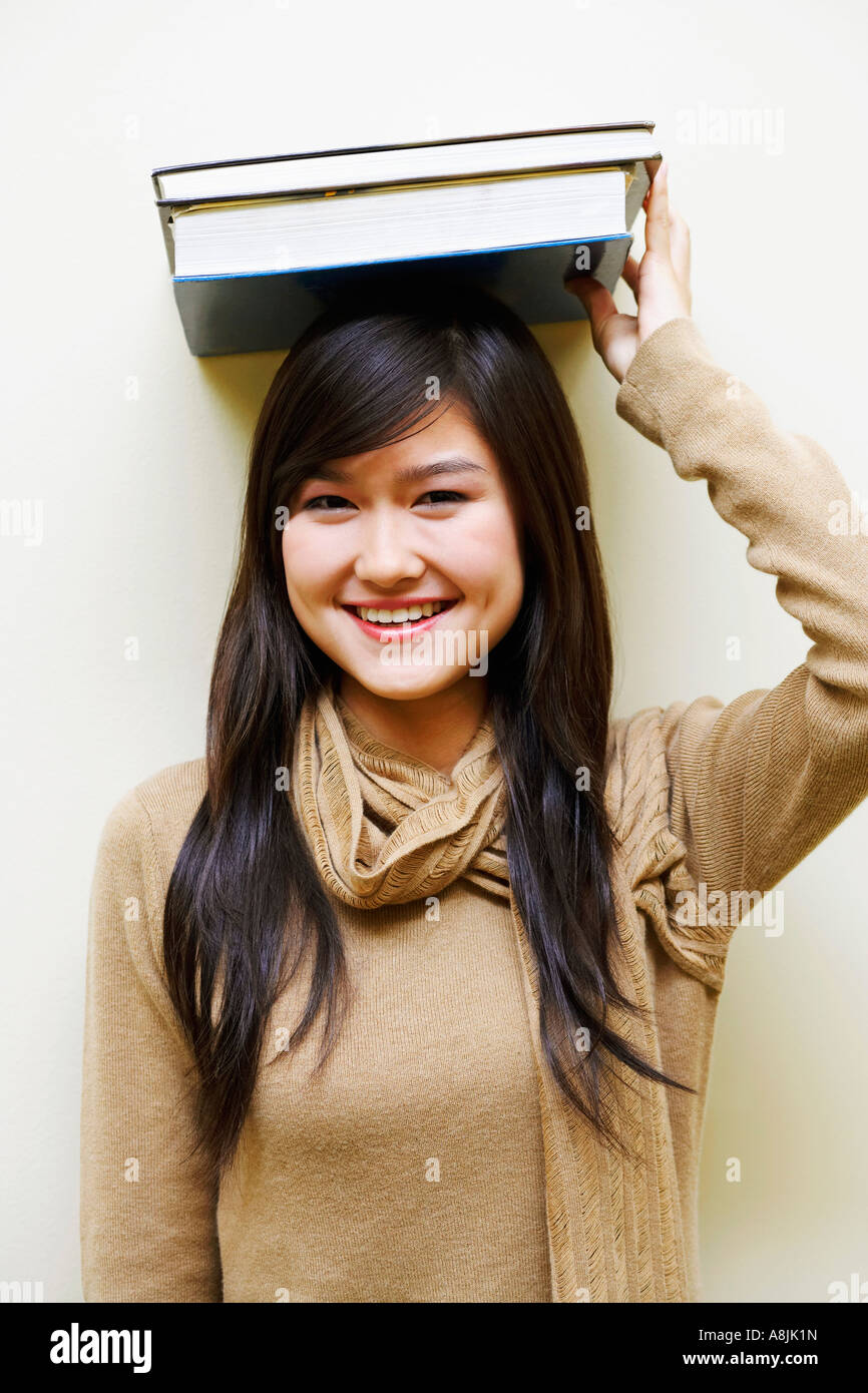 Portrait of a young woman holding books on her head Stock Photo - Alamy