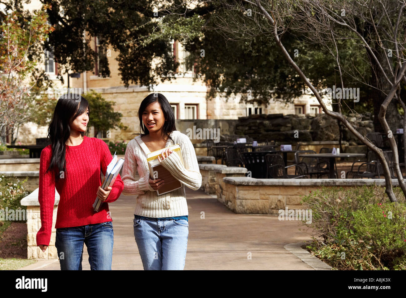 Two young women walking in a college campus Stock Photo