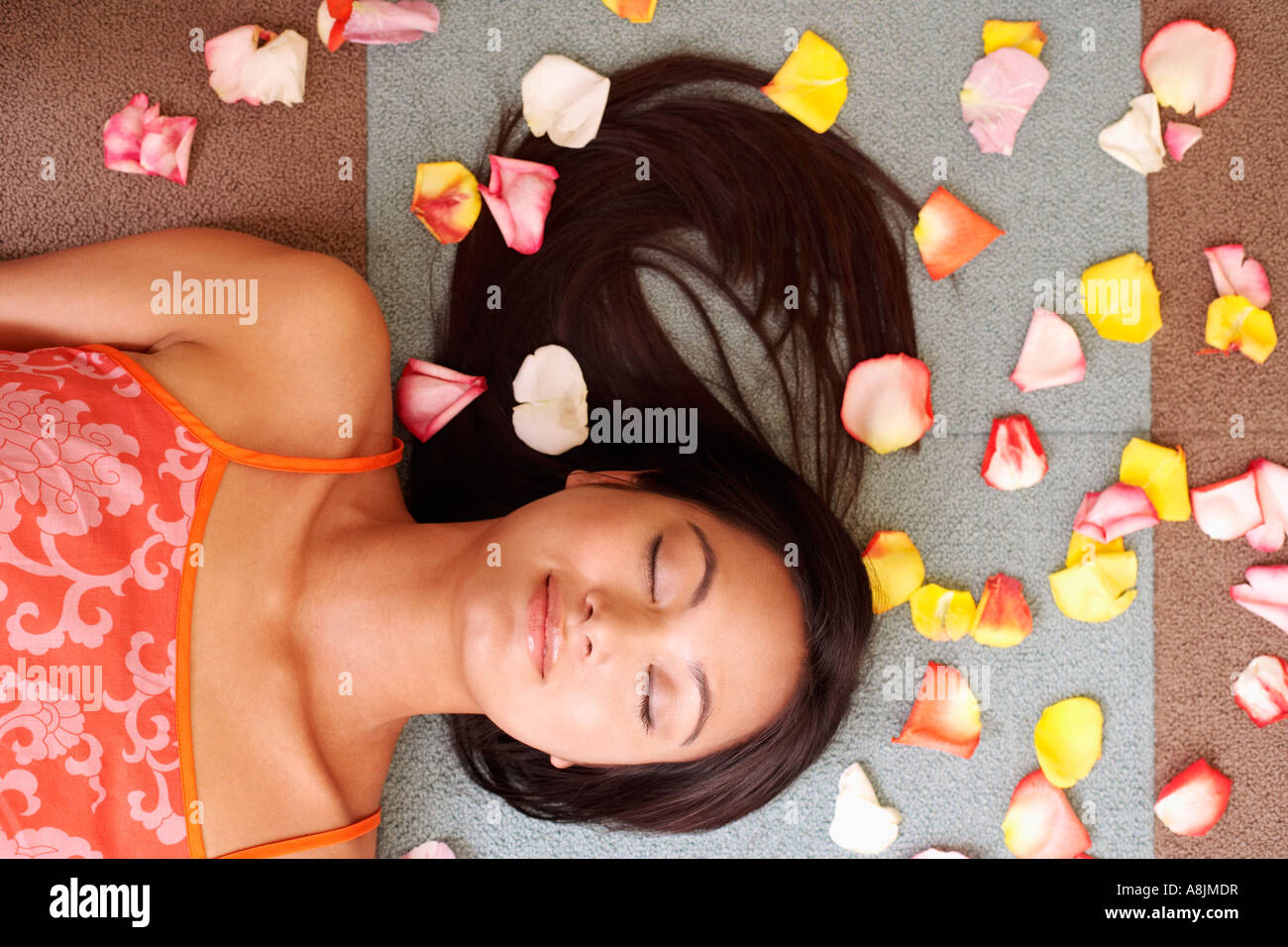 High angle view of a young woman lying down with petals around her Stock Photo