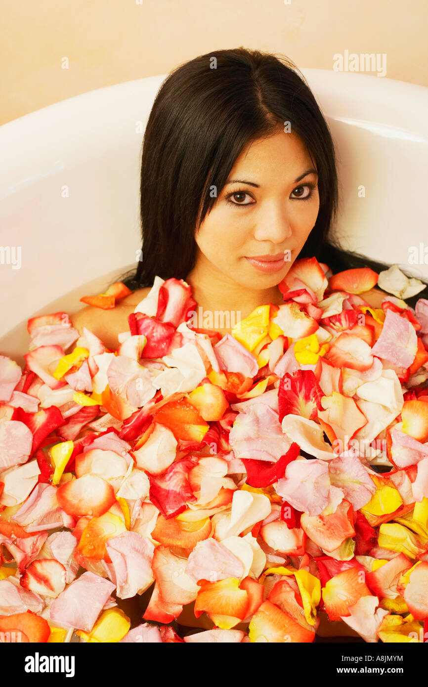 Portrait of a young woman in a bathtub filled with flower petals Stock
