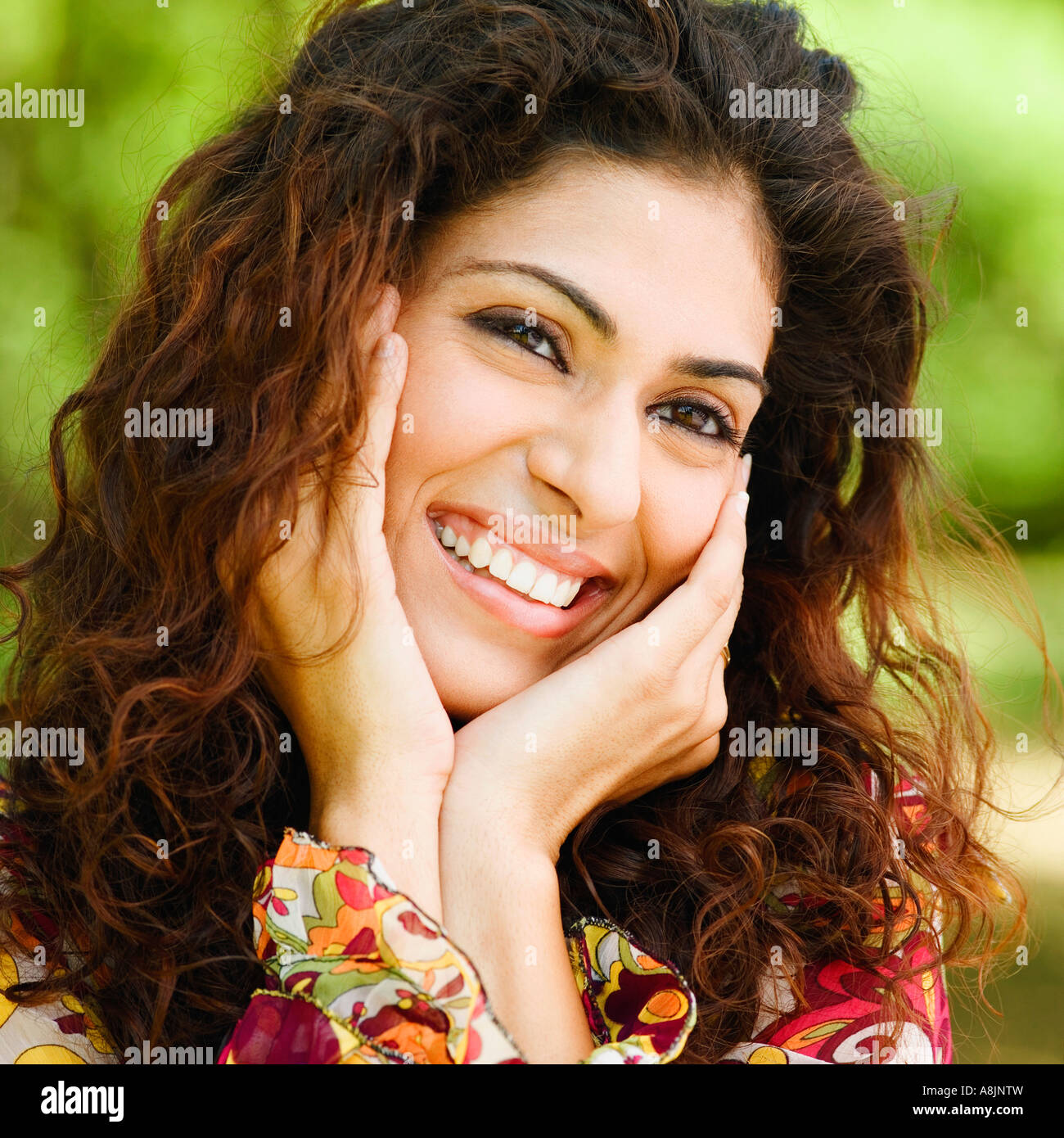 Portrait of a young woman smiling with her hand on her chin Stock Photo ...