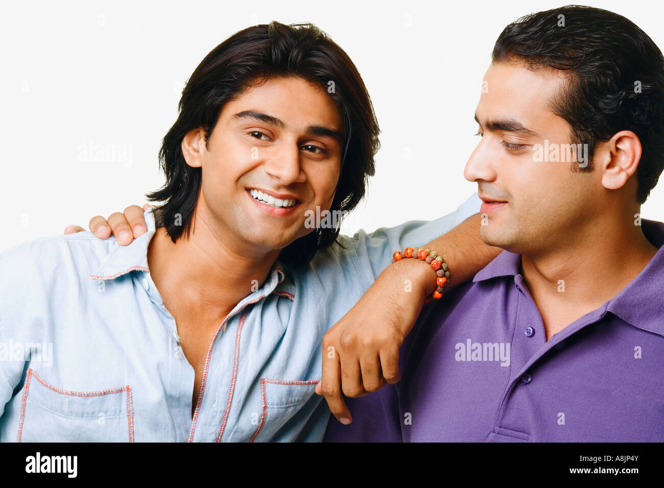 Close-up of two young men smiling with their arm around each other ...