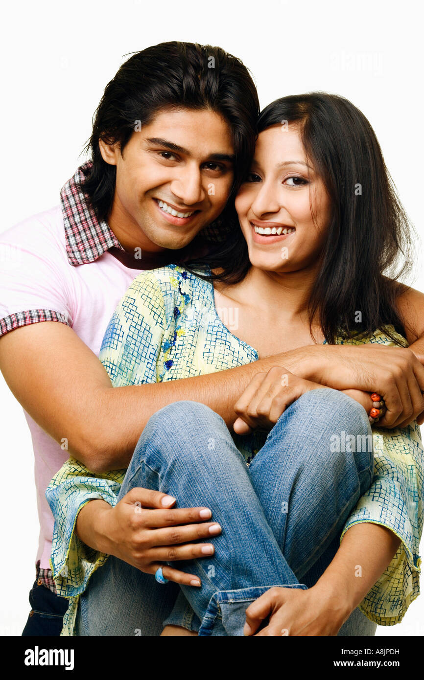 Portrait of a young man embracing a young woman from her behind and ...