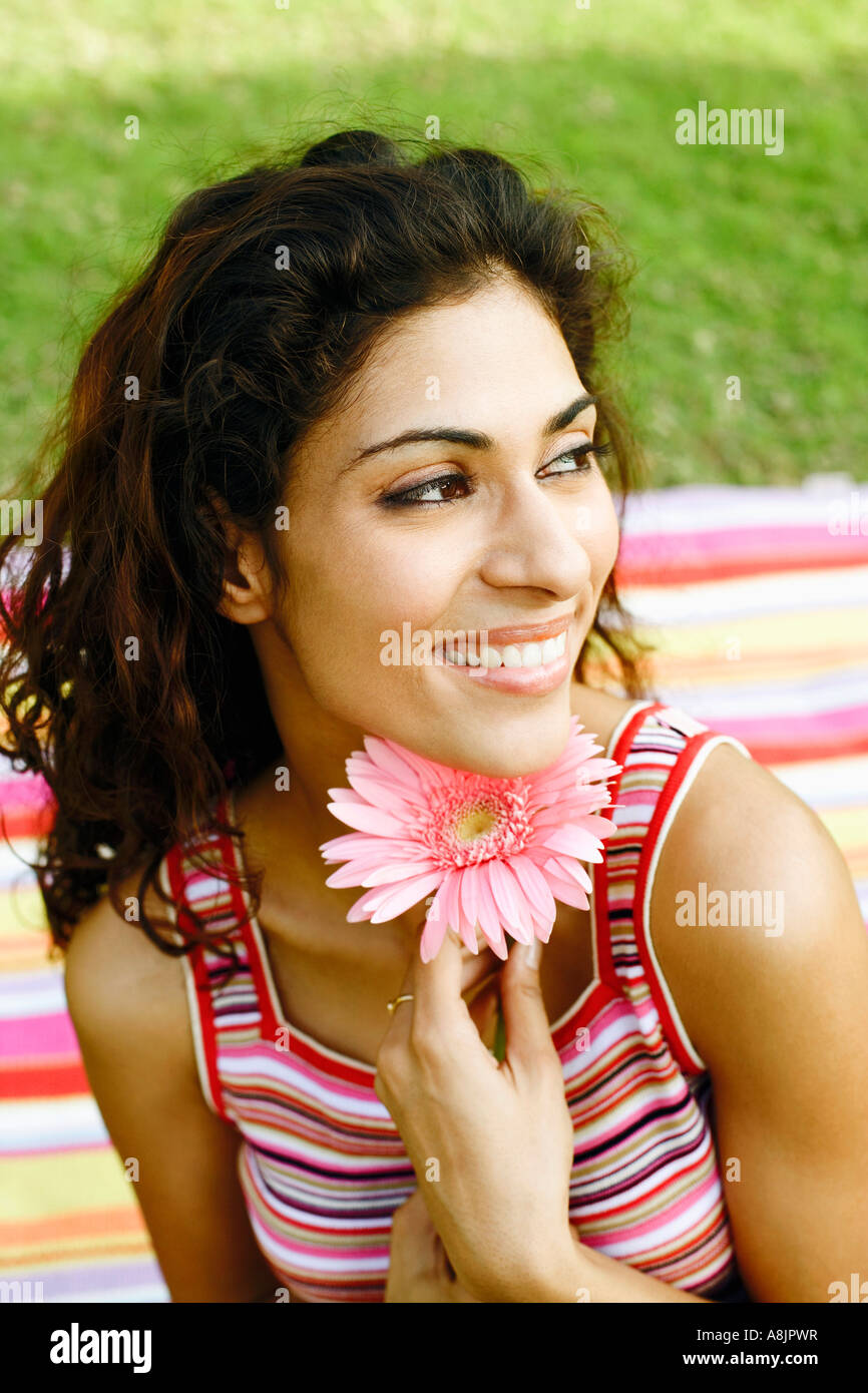 Close-up of a young woman holding a flower and smiling Stock Photo - Alamy