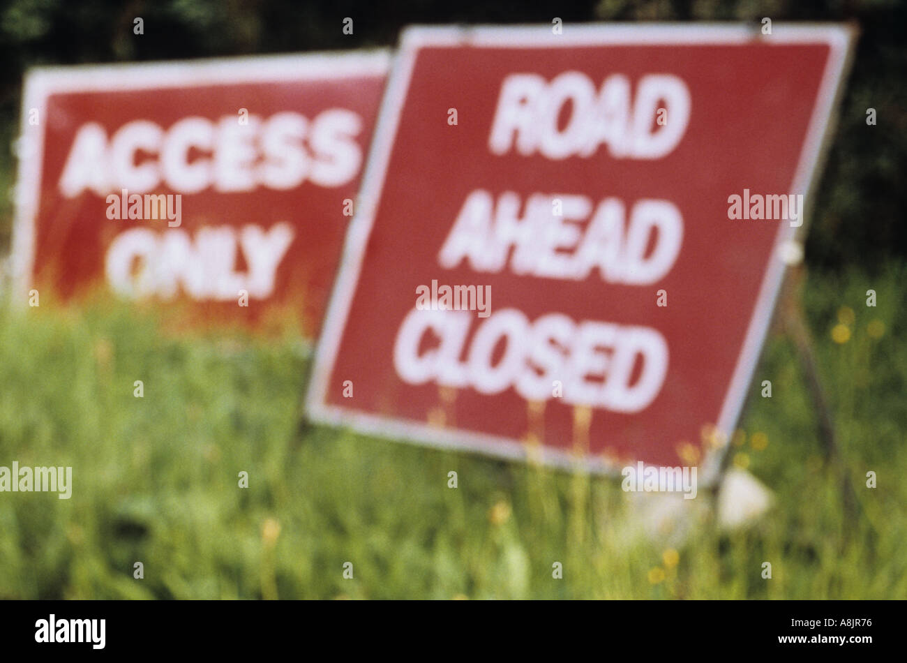 Defocussed temporary signs on grass verge saying Road ahead closed and Access only Stock Photo