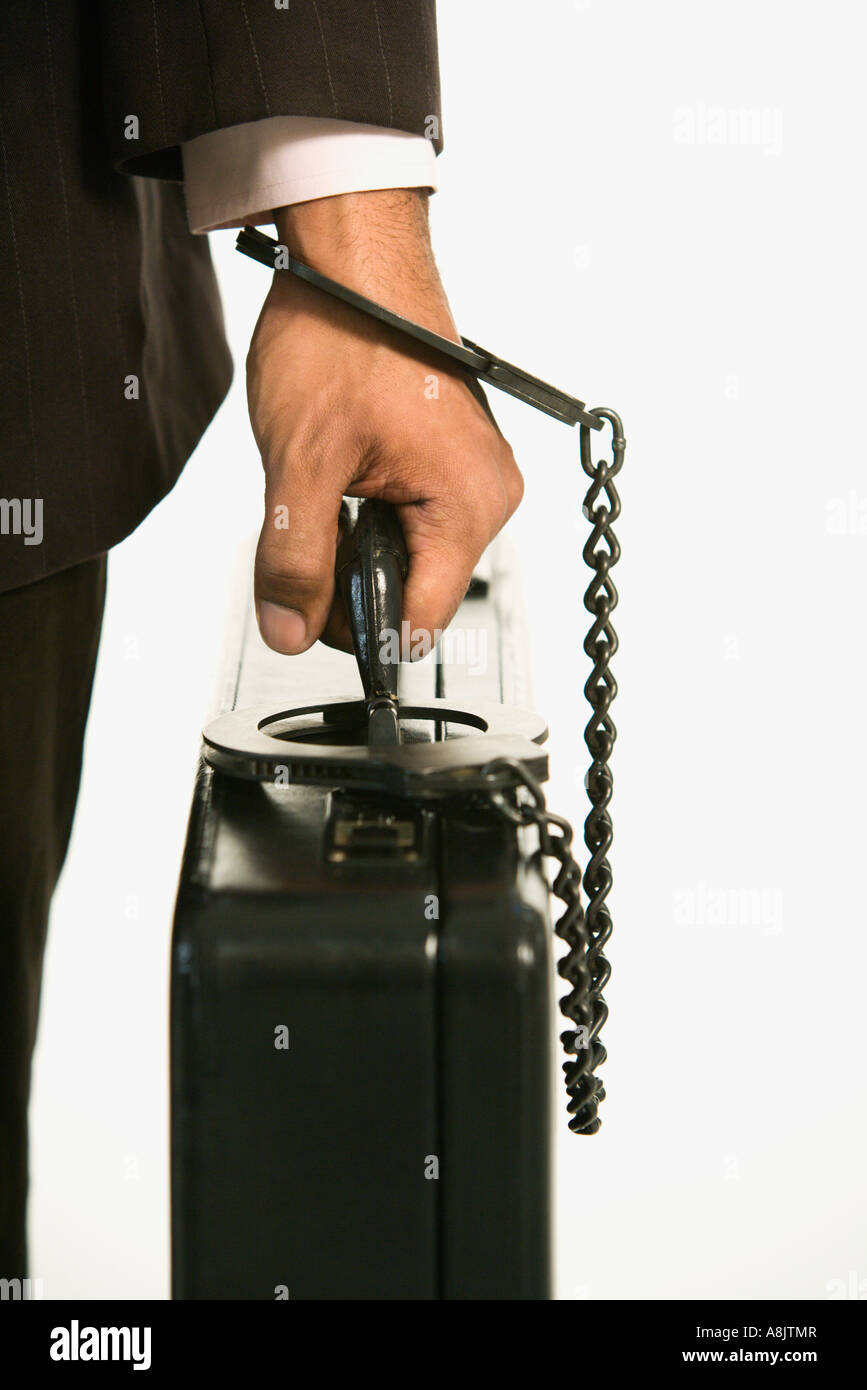 African American businessman in suit handcuffed to briefcase Stock