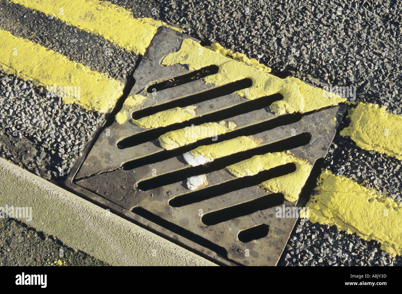 Double yellow lines at kerbside and painted across a drain grill UK Stock Photo