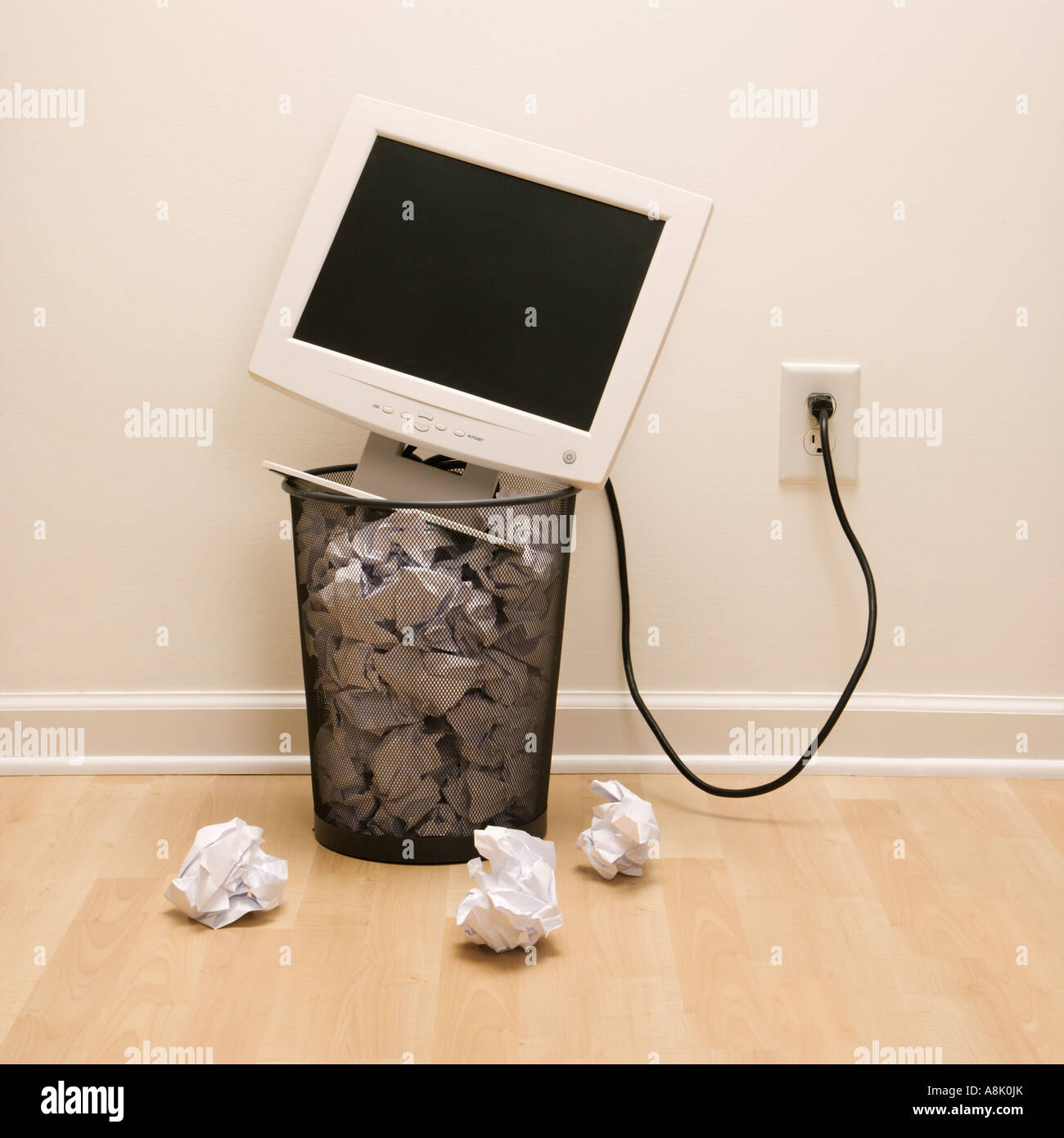 Computer monitor in trash can surrounded by crumpled up paper Stock