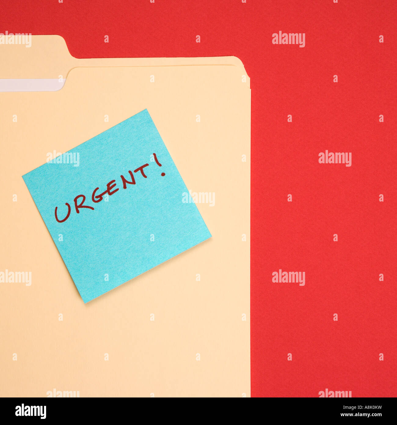 Folder with a blue sticky note attached reading urgent on a red ...