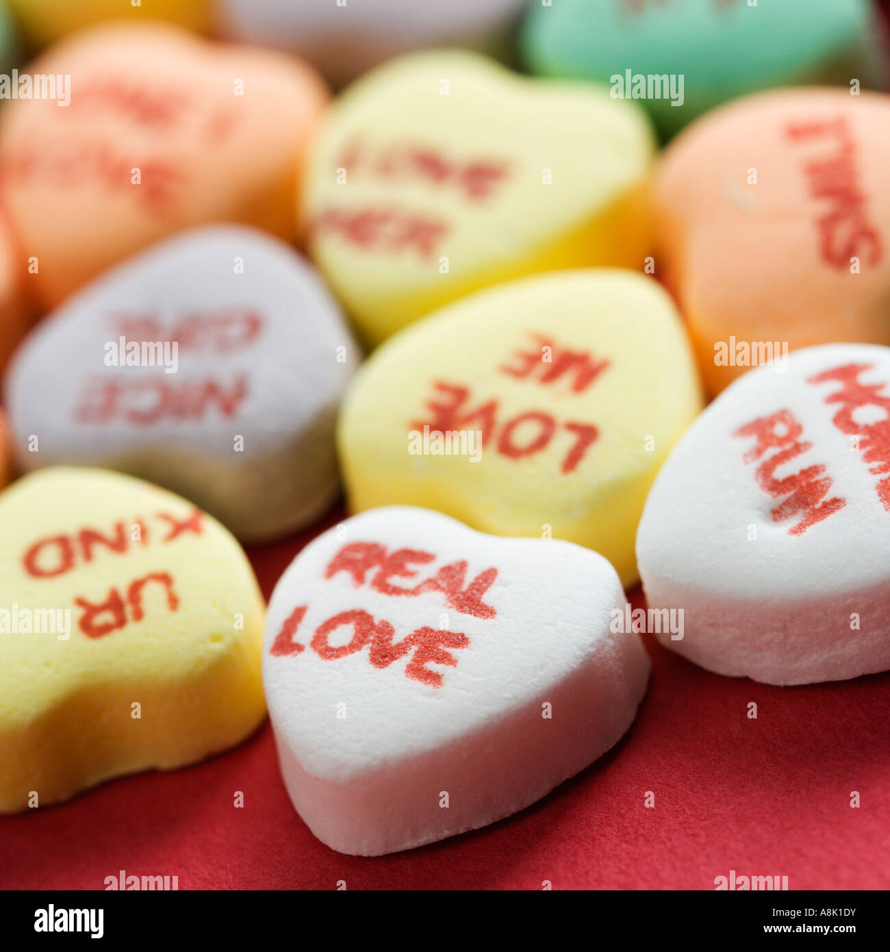 Colorful candy hearts with sayings on them arranged on red background Stock Photo