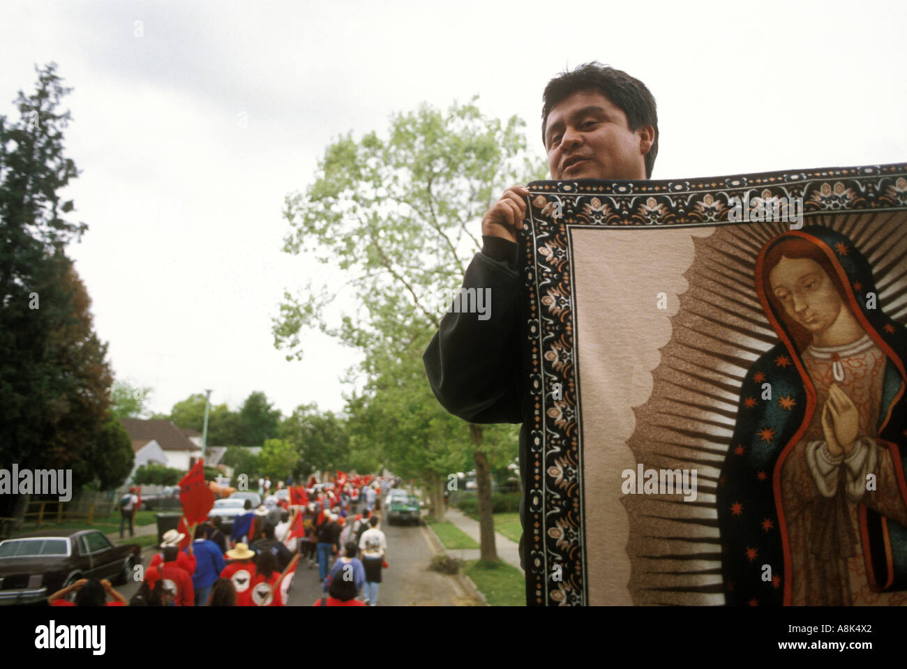 A United Farm Workers marcher holds an images of the Virgen of
