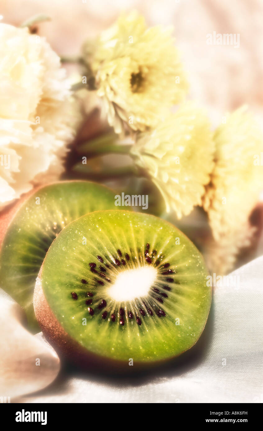 Still life of Kiwi fruit cut in half with background of white flowers Stock Photo