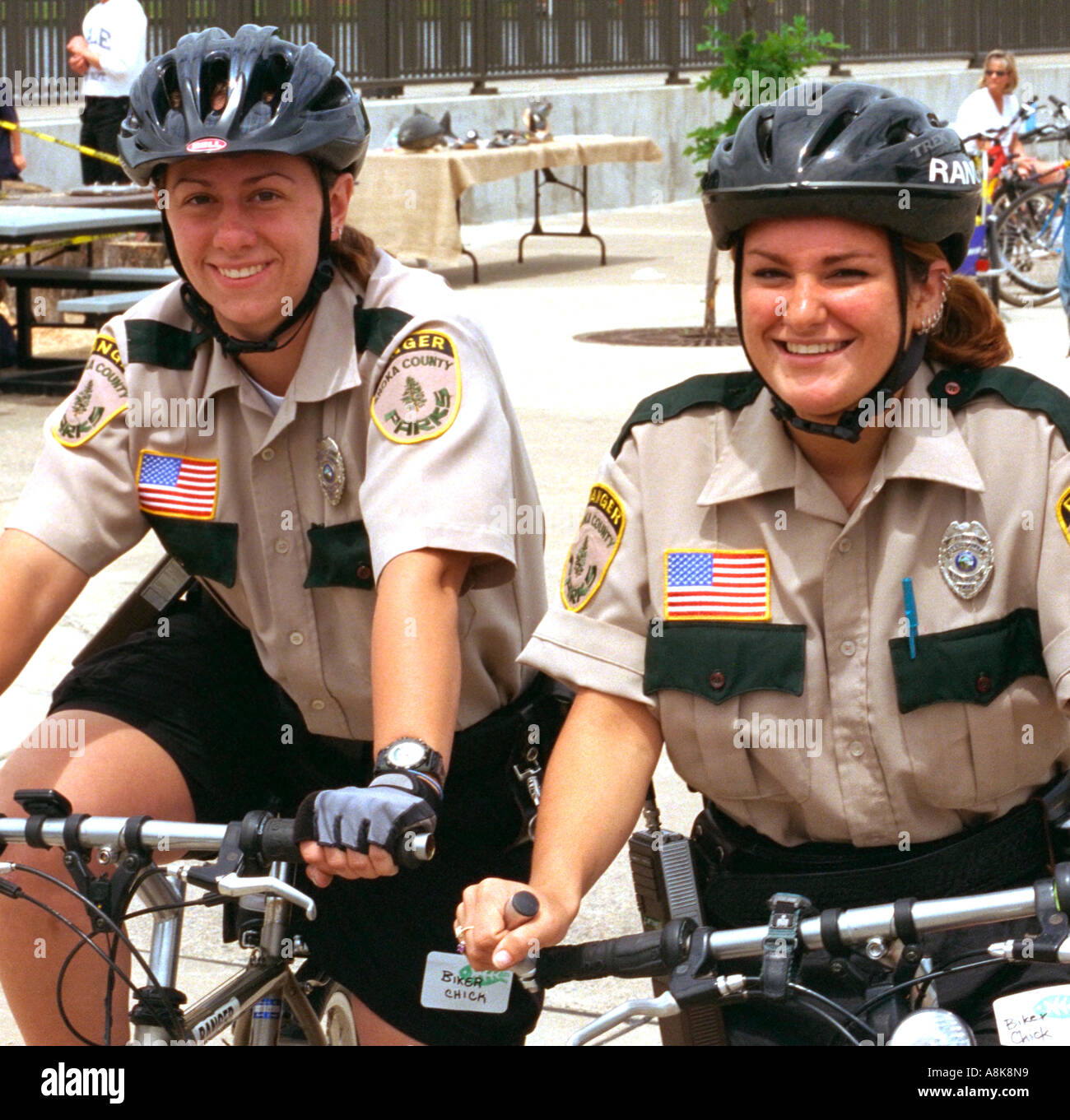Two happy park ranger police ladies age 28 patrolling Mississippi River Carp Festival. Brooklyn Park Minnesota USA Stock Photo