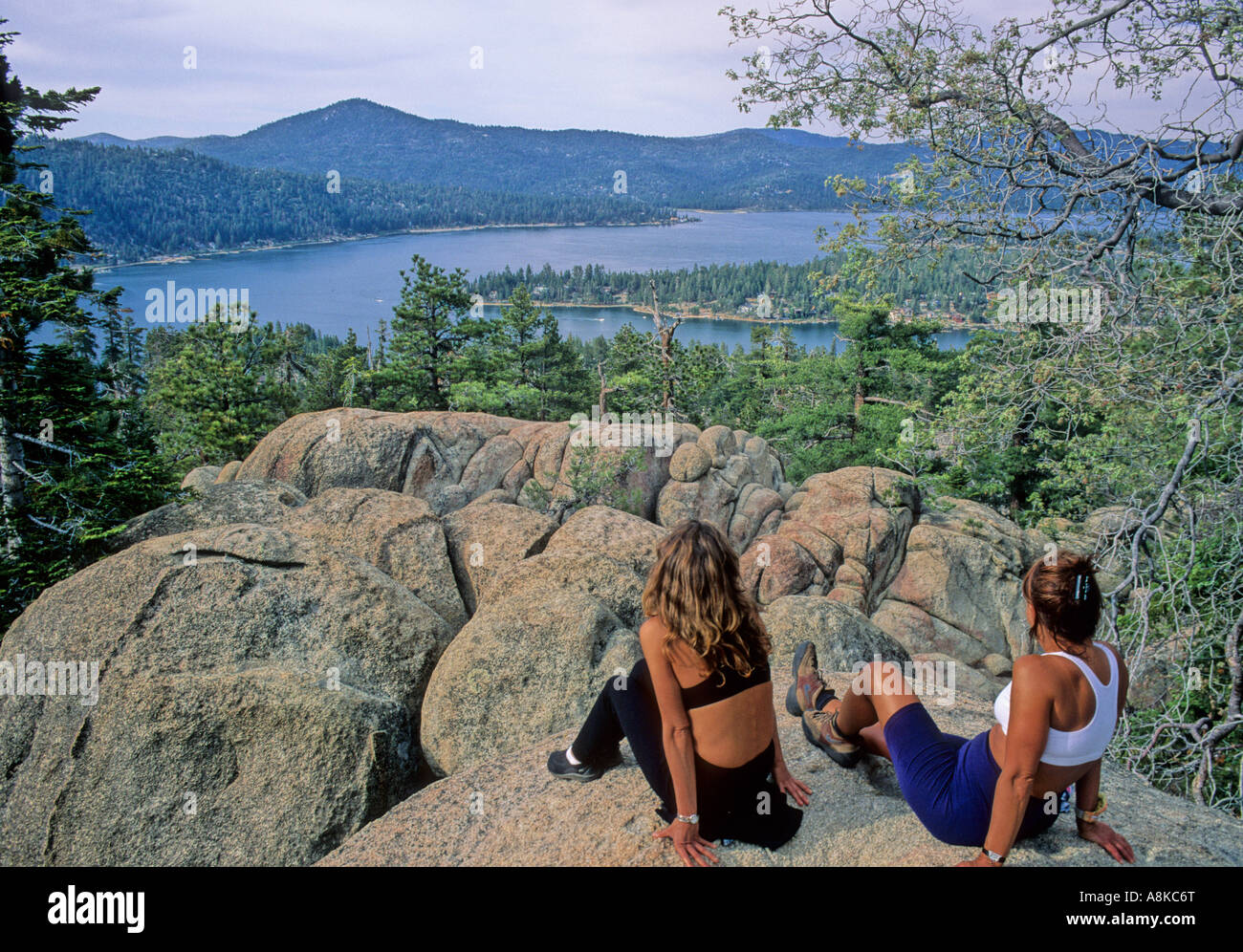 Women sitting on rocks look at Big Bear Lake in Southern California Stock Photo
