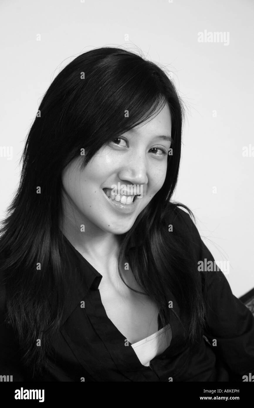 Black and white of smiling and pretty asian woman looking at the camera with a friendly and pleased expression Stock Photo