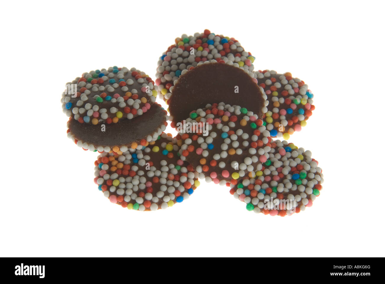 Horizontal close up of a pile of milk chocolate buttons on a white background. Stock Photo