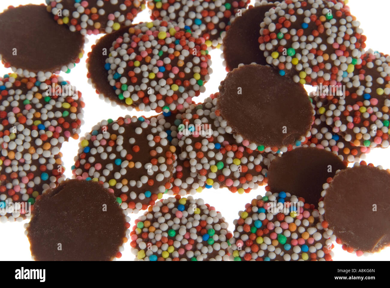 Horizontal elevated close up of a pile of milk chocolate buttons on a white background. Stock Photo