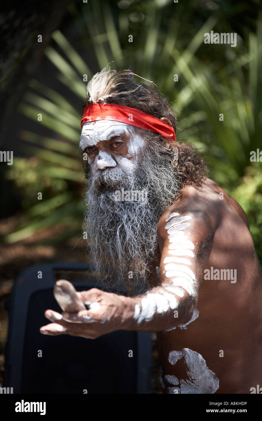 Aboriginal aborigine man with beard and face paint busking and