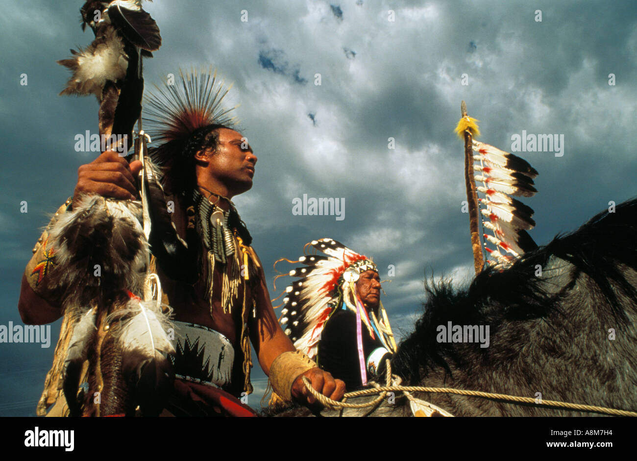 USA IDAHO Native American Men in Full Dress on Paint Horses against dark skies Shoshone Bannock Tribe MR Stock Photo