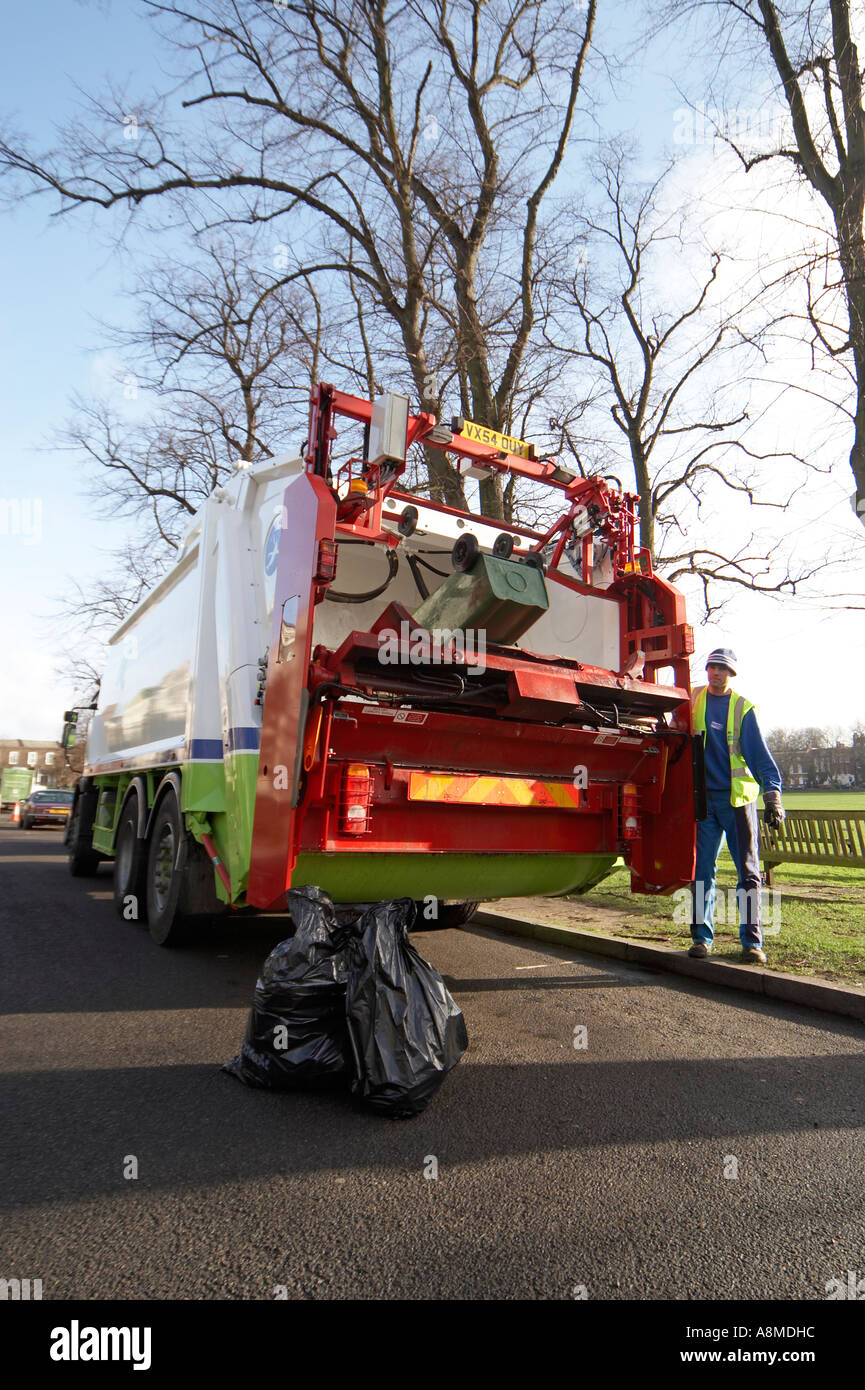 Waste rubbish or trash lorry or truck lifting green bin with man in