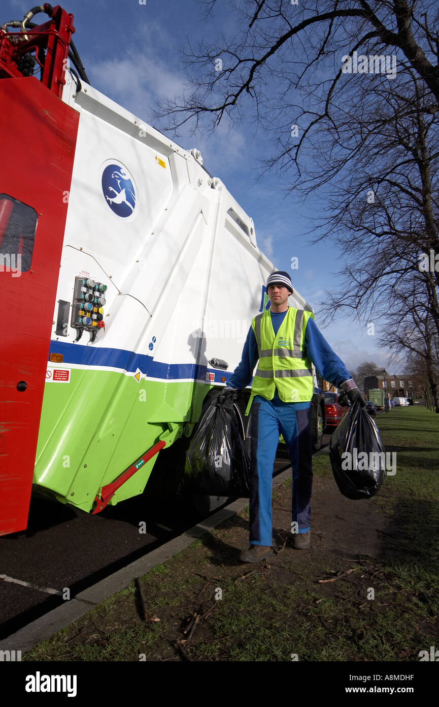 Waste rubbish or trash lorry or truck lifting green bin with man in