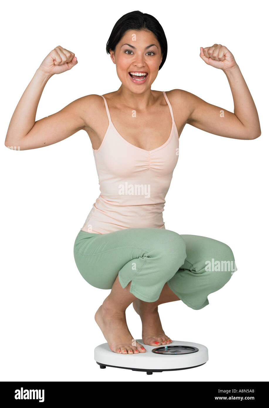 A woman weighing herself on a scale Stock Photo