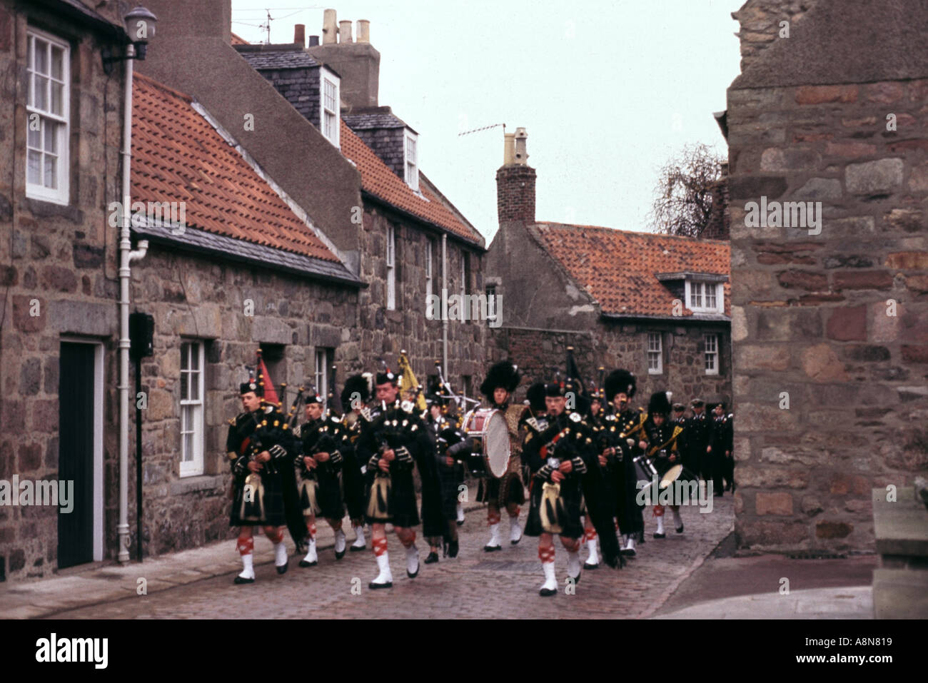 Pipers marching past old 17th and 18th century houses along the cobblestoned Don Street of Old Aberdeen Scotland  Stock Photo