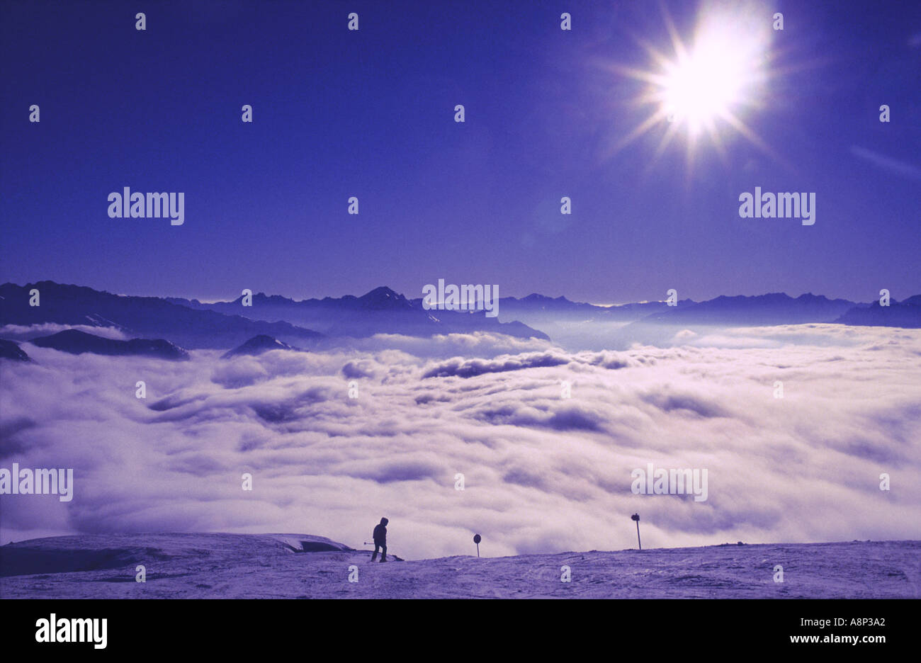 A lone skier above a sea of clouds at  the ski resort La Plagne, Savoie, France. Stock Photo