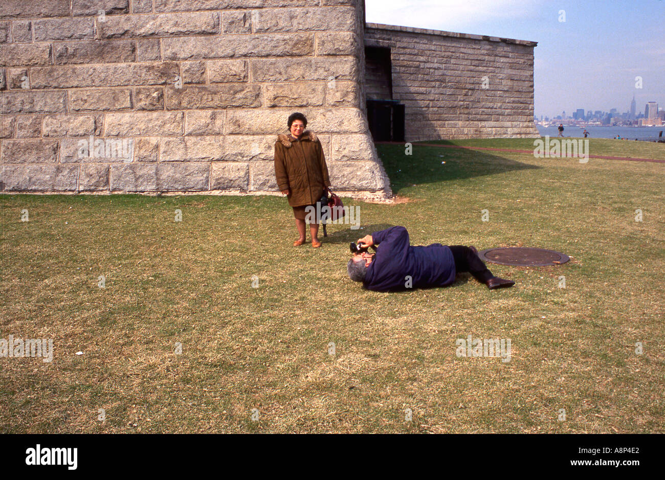 A woman has her photograph taken at the base of the statue of liberty in New York Stock Photo