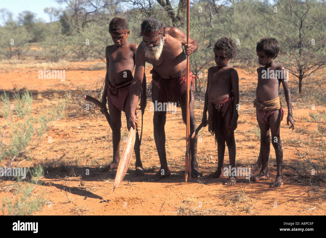 Aboriginal elder teaching young boys to hunt points to