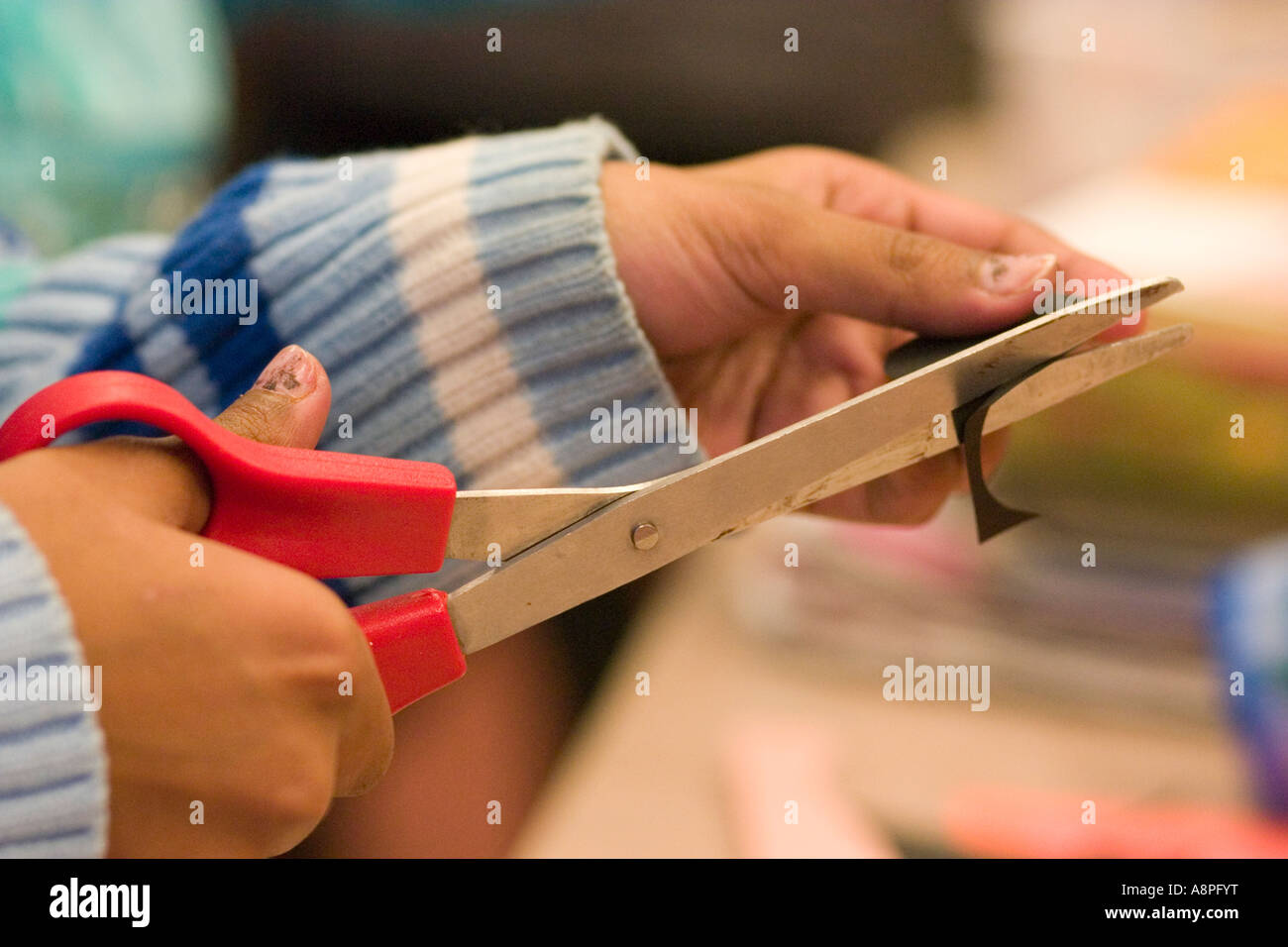 2 year old blonde girl cutting paper with blue children's scissors Stock  Photo - Alamy