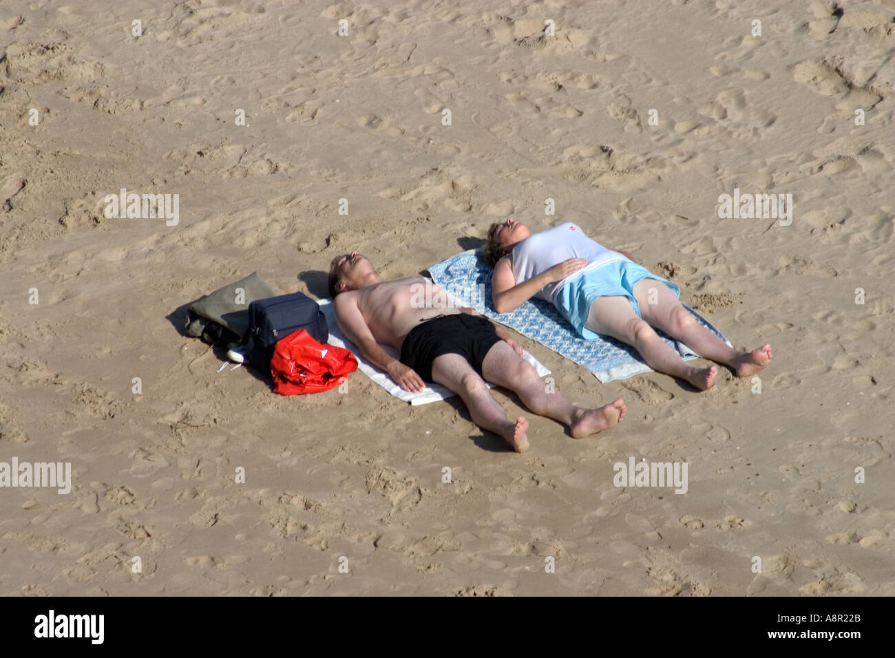 Couple Sunbathing Tenby Pembrokeshire Wales UK Stock Photo