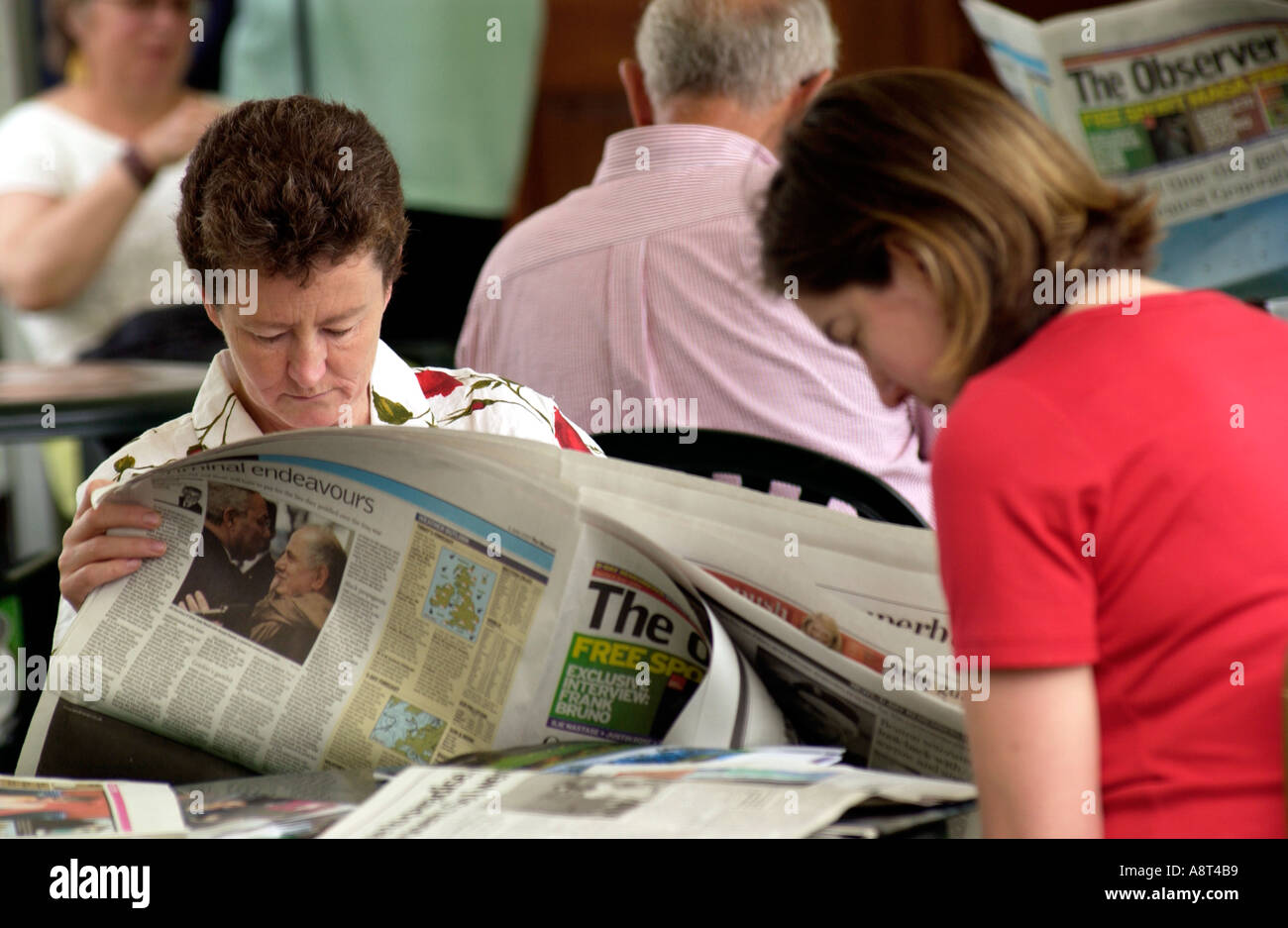 Woman sitting reading broadsheet newspaper at Hay on Wye Literature Festival Powys Wales UK Stock Photo