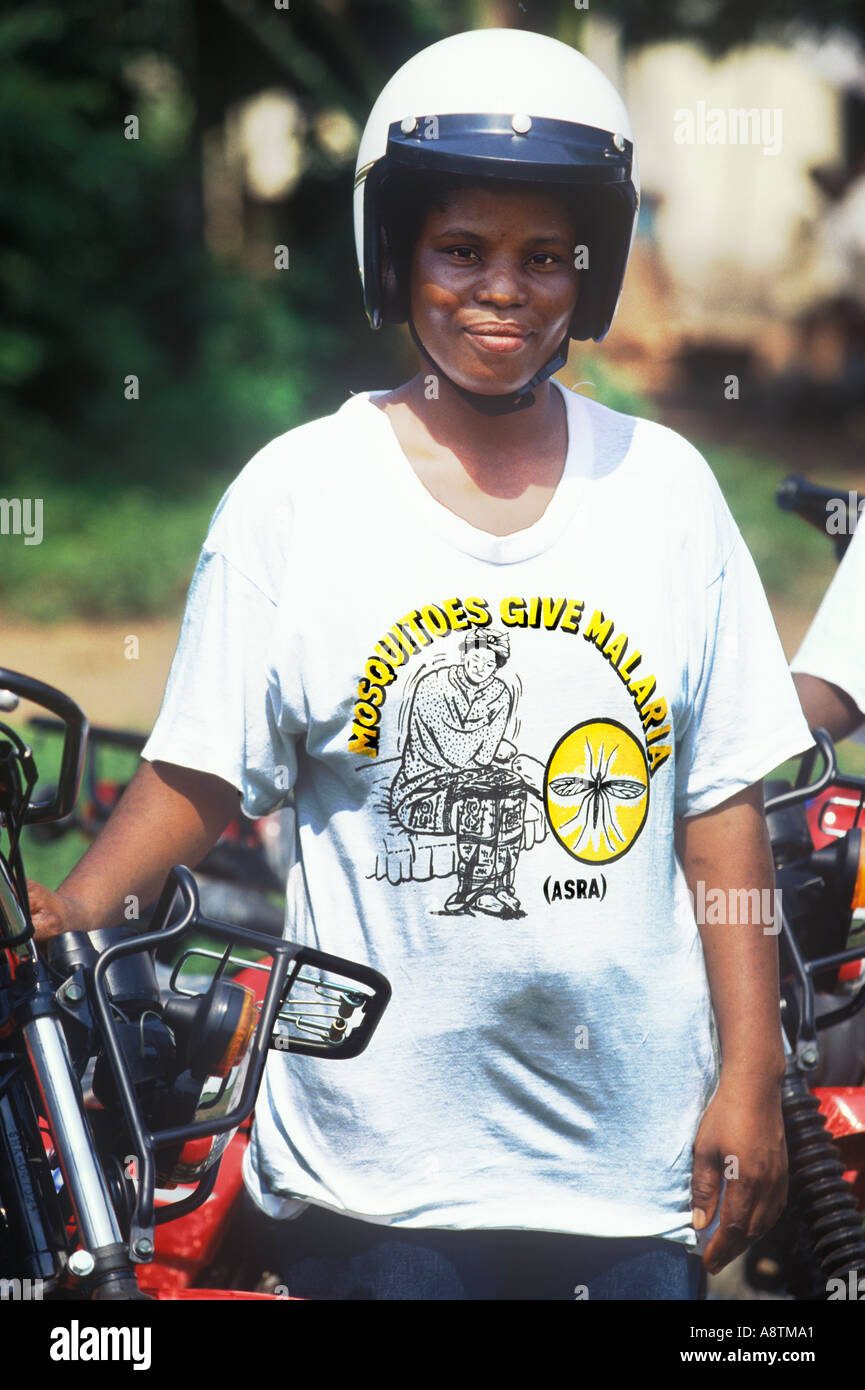 A Ghanaian health worker with a motorcycle for reaching remote areas wears a tee shirt with a message about malaria Stock Photo