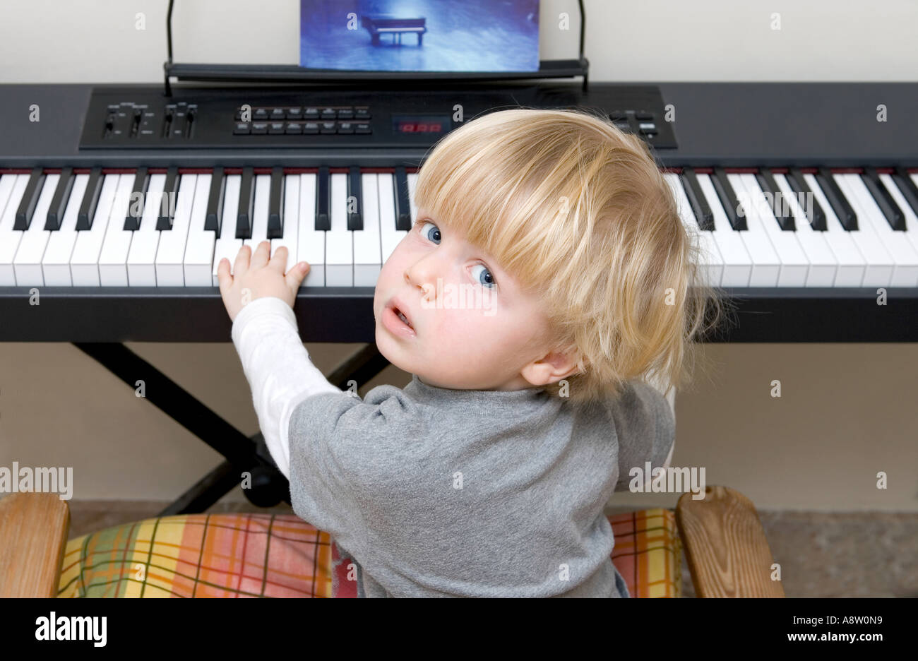 Young boy playing electric piano or keyboard and looking at the camera Stock Photo