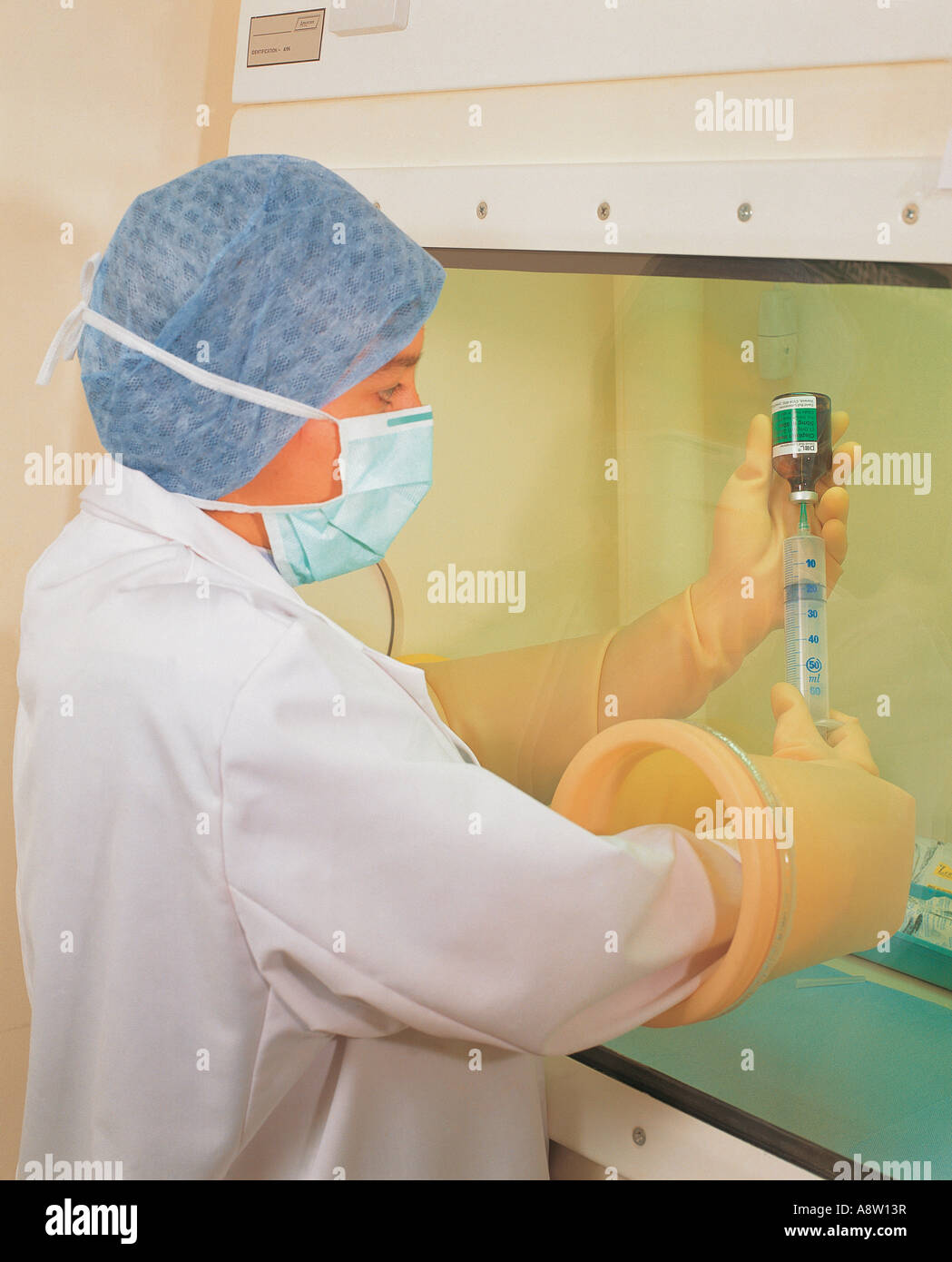 Hospital nurse preparation of chemotherapy injection hazardous chemicals in safe handling laboratory cabinet. Stock Photo