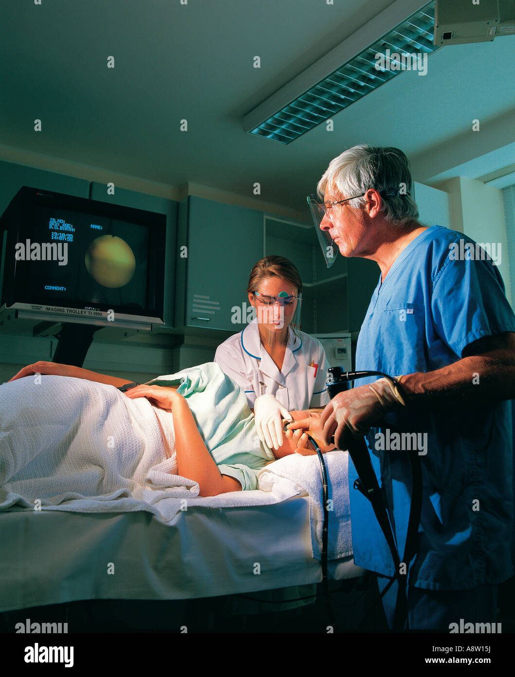Surgeon and nurse undertaking endoscopy procedure on female patient in