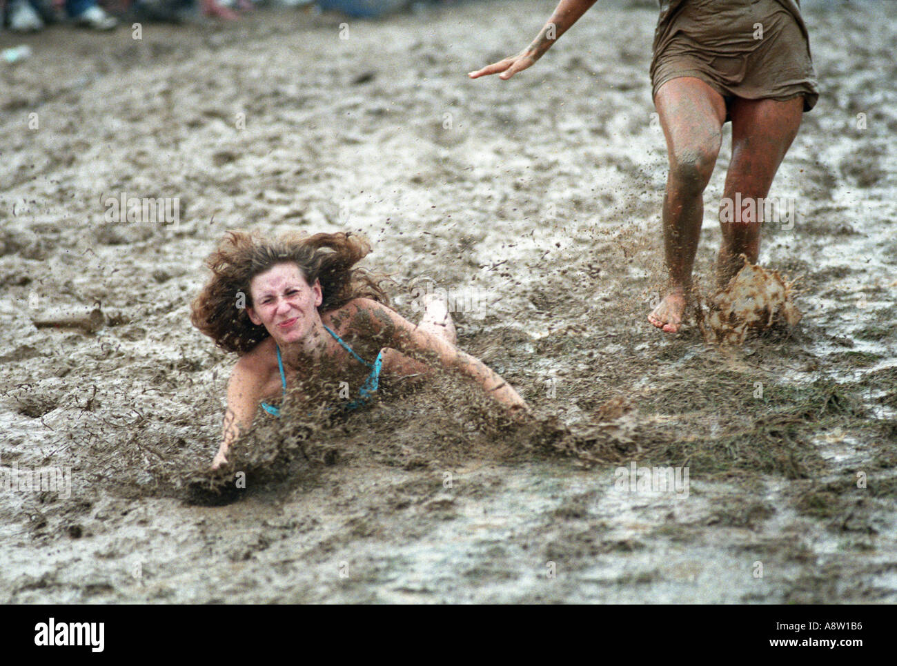 Humor fall Woodstock music festival 1994 Woman falling in mud sliding down muddy hill Stock Photo