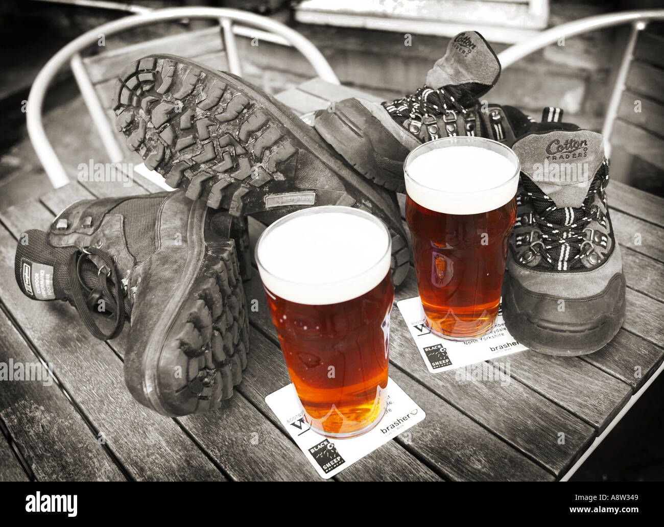 Pints of beer and walking boots on a wooden pub table outside UK - walking holiday concept Stock Photo