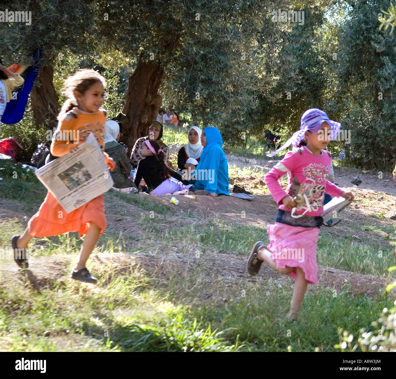 Children playing whilst family has a picnic under the Olive trees in the Jardin de la Menara Marrakech Stock Photo