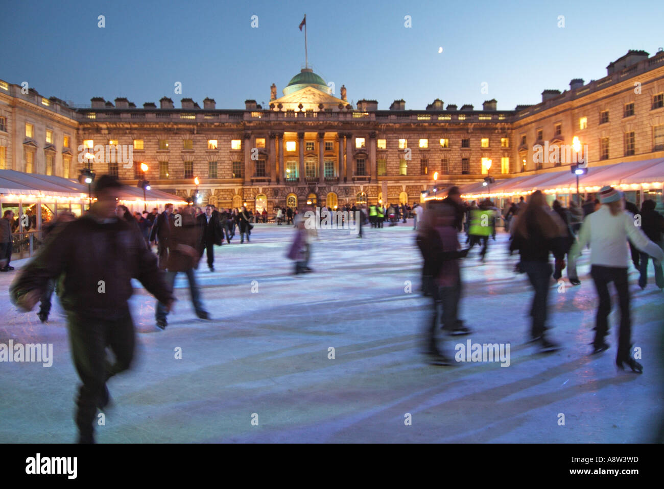 Adults & kids ice skaters with backdrop historical Somerset House building & courtyard on temporary winter ice skating rink Strand London England UK Stock Photo