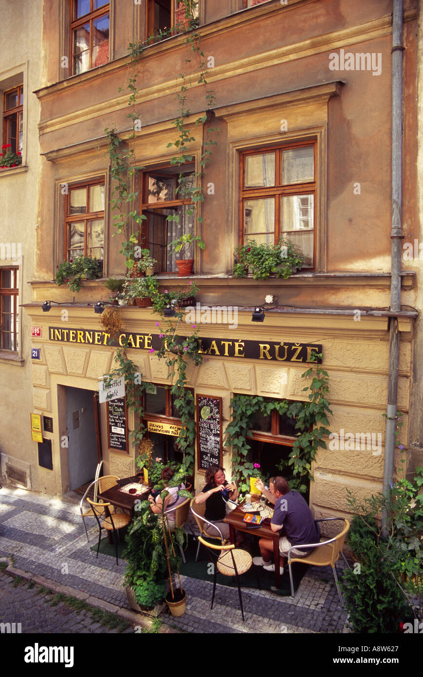 View from an elevated position of people sitting at tables outside an internet cafe in Prague with trailing plants on the three storey building Stock Photo