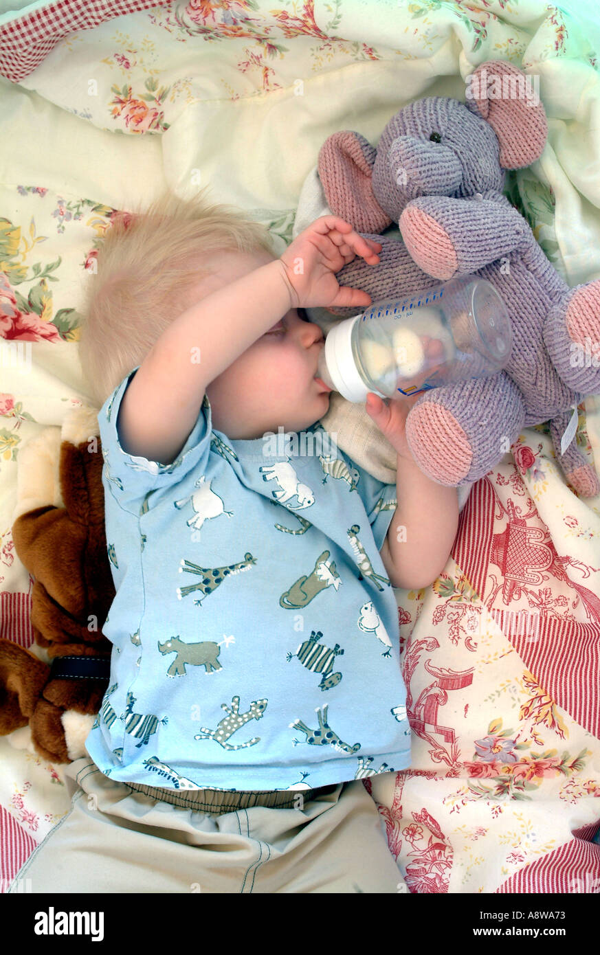 An eightmonth old baby boy sleeping in his cot with his bottle still