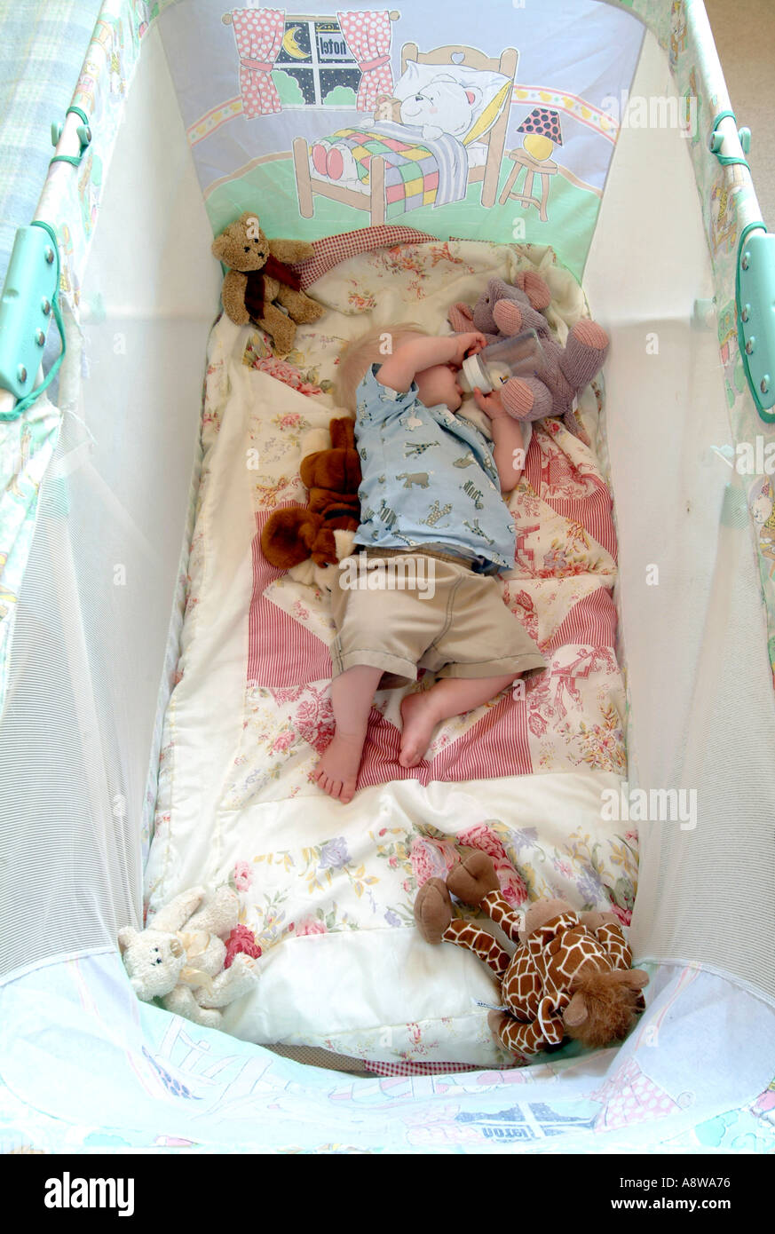 An eightmonth old baby boy sleeping in his cot with his bottle still