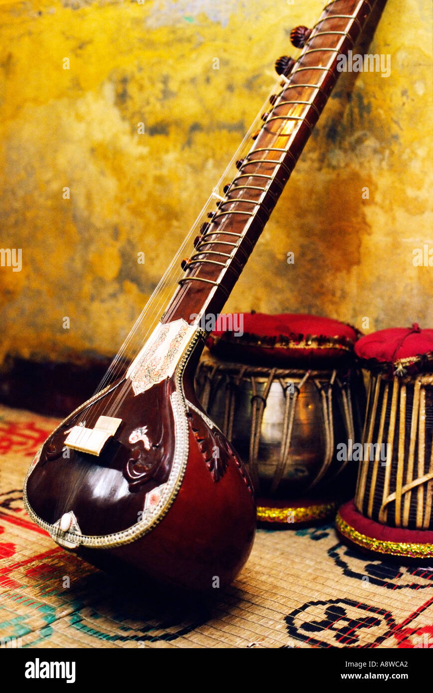 Indian musical instruments a SITAR and TABLA DAGGA drums on carpet standing against a yellow wall Stock Photo
